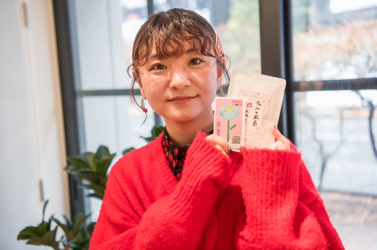 写真:完成した入浴剤とメッセージカードを手に笑顔を見せるま ち こさん
